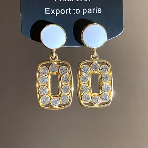 Close-up of elegant gold square hollow drop earrings with sparkling rhinestones