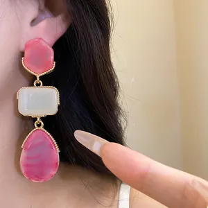 Close-up of vintage resin drop earrings featuring pink and cream stones on model.