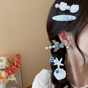 Detail showing ocean-themed shell and starfish hair clips with pearls on braided hair.