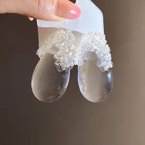 Dettaglio di orecchini a goccia in resina trasparente con eleganti decorazioni perlate