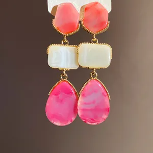 Close-up of vintage resin drop earrings featuring pink and white marble patterns.