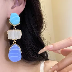 Detail view of vintage resin pendant earrings with blue and white geometric layers