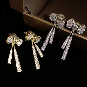 Elegant 14k gold plated zircon bow earrings featuring a delicate dangling pendant design