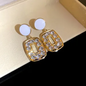Close-up of vintage gold hollow square earrings with sparkling rhinestones