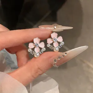 Detailed close-up of pink enamel flower earrings featuring zircon and pearl accents