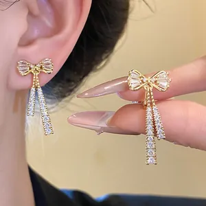 Detailed view of 14k gold plated bow knot tassel earrings with sparkling cubic zirconia