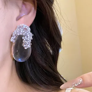 Dettaglio di eleganti orecchini a goccia in resina con delicati dettagli di perle bianche