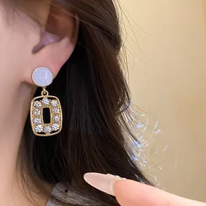 Detail view of vintage gold drop earrings with crystals and rectangular hollows