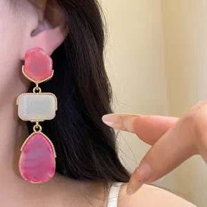 Close-up of vintage style resin geometric pendant earrings featuring pink and cream stones