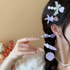 Detailed view of purple sea star and shell resin hair clips styled on braided hair