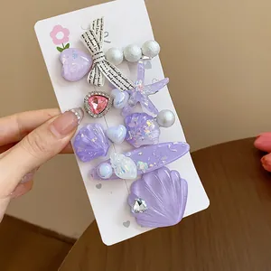 Detail view of purple resin hair clips set with starfish, seashells and pearl accents