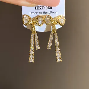 Macro close-up view of 14k gold plated bow clip-on earrings with sparkling zircon tassels
