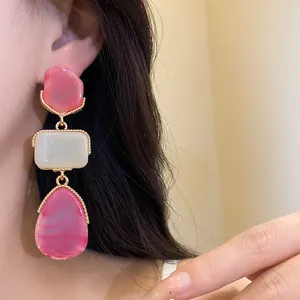 Close-up of vintage-style three-tiered resin teardrop earrings worn by an Asian model.