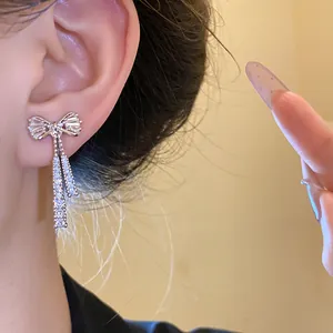 Detailed close-up showing the sparkling zircon bow-knot pendant earrings on the ear.