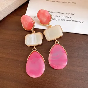 Detailed view of vintage resin drop earrings with pink waterdrop and white square pendants.