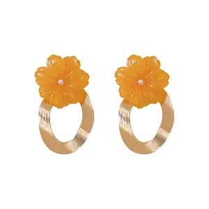 Elegant orange resin flower earrings featuring gold textured oval hoops and pearl centers