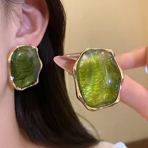 Pendientes ovalados de resina verde con borde dorado y textura elegante estilo vintage.