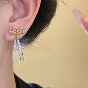 Detailed view of elegant 14k gold-plated bow earrings with sparkling zircon tassels