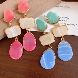 Close-up of vintage resin drop earrings featuring colorful geometric stones and gold frames