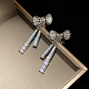 Close-up of sparkling zirconia bow-knot earrings with tassel detail on a jewelry box.