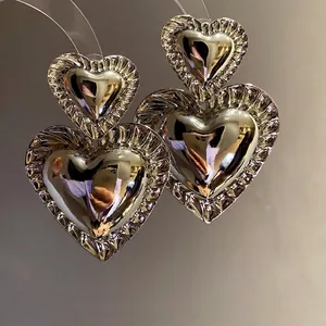 Retro exaggerated silver metallic double heart drop earrings with luxury finish.