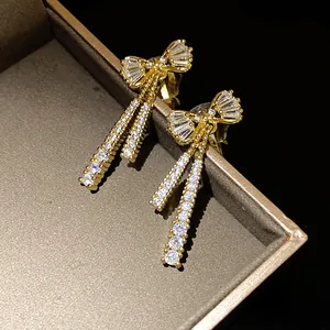 Close-up of elegant gold bow clip-on earrings with shimmering zircon tassel drops