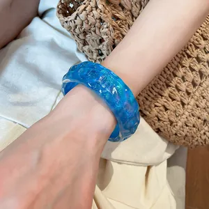 Detailed view of a blue irregular resin bangle featuring glitter, worn for island resort style