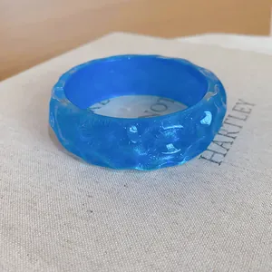 Close-up of blue translucent resin bangle with irregular hammered surface texture.