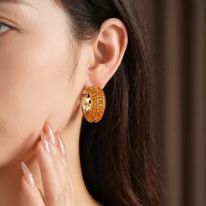 Elegant gold-plated geometric hoop earrings with amber stones worn by an Asian model