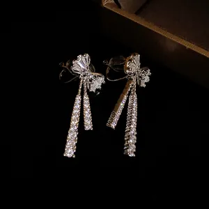 Macro view of sparkling zircon bow-knot dangle clip-on earrings in gold finish