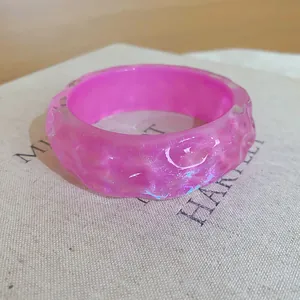 Close-up detail of a translucent pink resin bangle with unique irregular bumpy texture