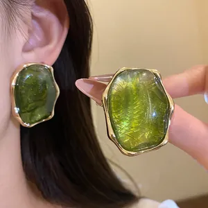 Detalle de pendientes ovalados de resina verde con marco dorado de estilo vintage