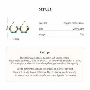Detailed view of vintage gold plated C-shaped earrings with turquoise and zircon stones