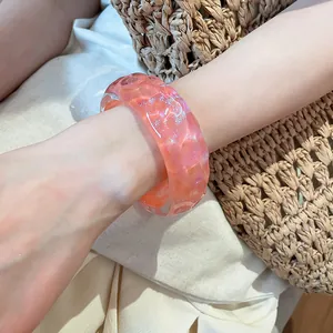 Close-up of pink resin bracelet with irregular bumpy texture and subtle glitter finish.