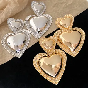 Macro detail of vintage gold and silver chunky heart earrings on a stylish background.