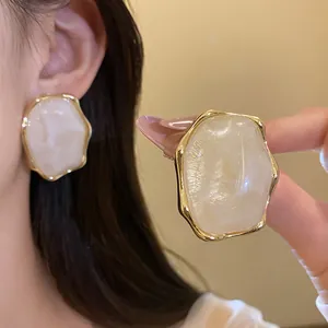 Primer plano de pendientes de resina ovalados elegantes con bordes dorados texturizados