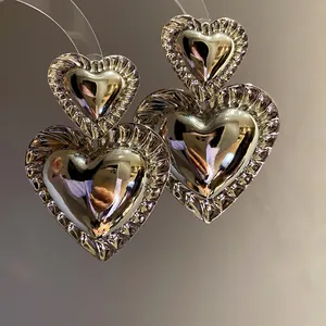Detailed macro view of vintage double heart pendant earrings with ruffled silver edges