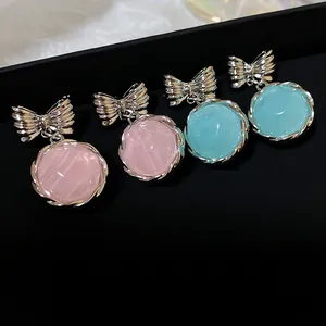 Close-up detail showing sweet pink and turquoise bow drop earrings on black display stand