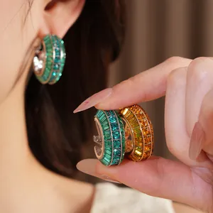 Detailed macro view of silver needle hoop earrings featuring green and amber crystals