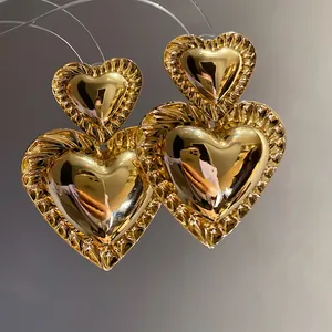 Detailed close-up view of vintage gold-toned double heart drop earrings with ruffled texture.