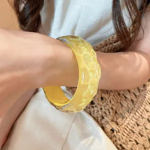 Close-up view of a thick translucent yellow resin bracelet with irregular bumpy texture
