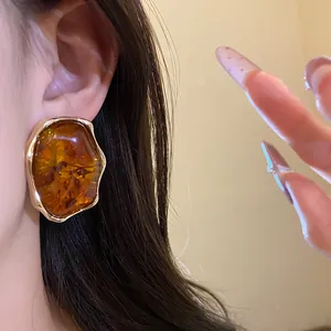 Pendientes elegantes de resina ámbar estilo vintage con borde dorado en una modelo