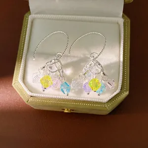 Dettaglio di eleganti orecchini a fiore traforato con nappe di perline di vetro colorate