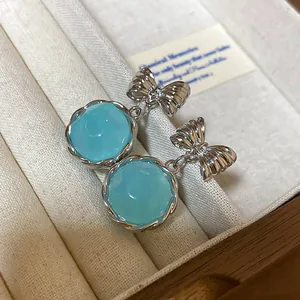 Close-up of sweet Korean style light blue round drop earrings with silver bow detail.