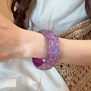 Close-up of purple glitter resin bangle with irregular textured surface on wrist.