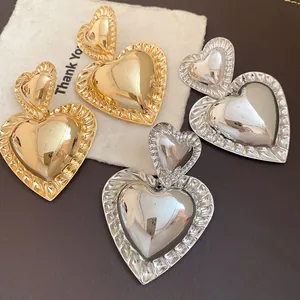 Detail showing retro oversized heart pendant earrings in gold and silver metallic finishes.