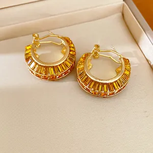 Close-up of luxurious golden hoop earrings featuring amber baguette crystals in a jewelry box