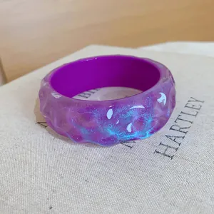 Detail of purple resin bangle with blue glitter and moon pattern on irregular surface