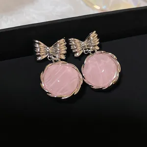 Detailed macro view of sweet pink marble drop earrings with silver bowknot studs