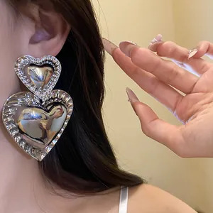 Detailed view of oversized vintage silver heart dangle earrings worn by a model.